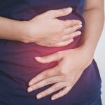 Midsection Of Woman Hands On Aching Stomach Against White Background